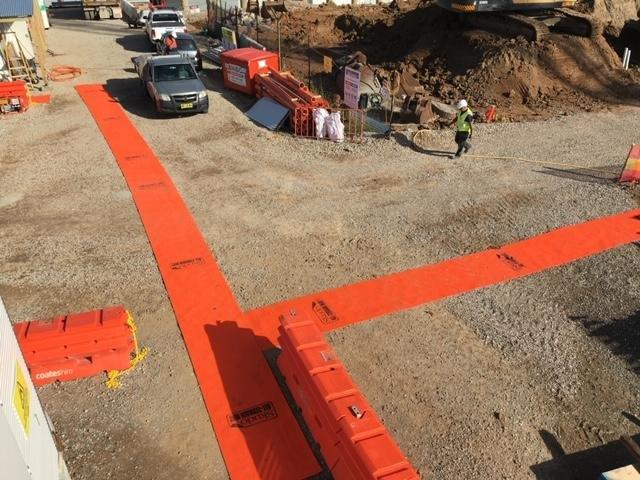 Construction site utilizing an all-terrain construction mat from SkudoUSA to form a safe walkway for workers