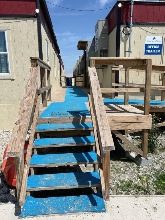 Blue temporary ground protection mats installed under wooden steps to create a safe walkway over gravel during construction