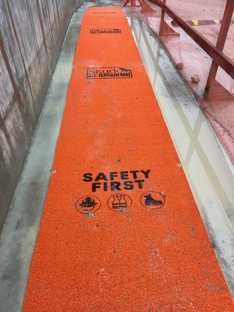 orange protection mat installed over a wet concrete walkway