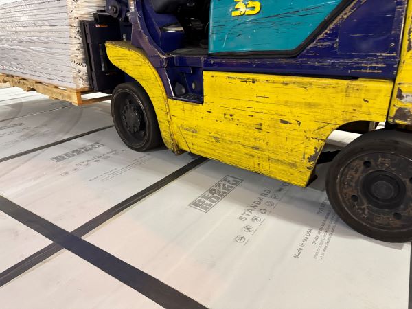 forklift carrying heavy cargo running over grey floor protection boards