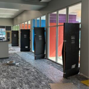 a carpeted hallway under construction with open windows and doors covered with black protective material